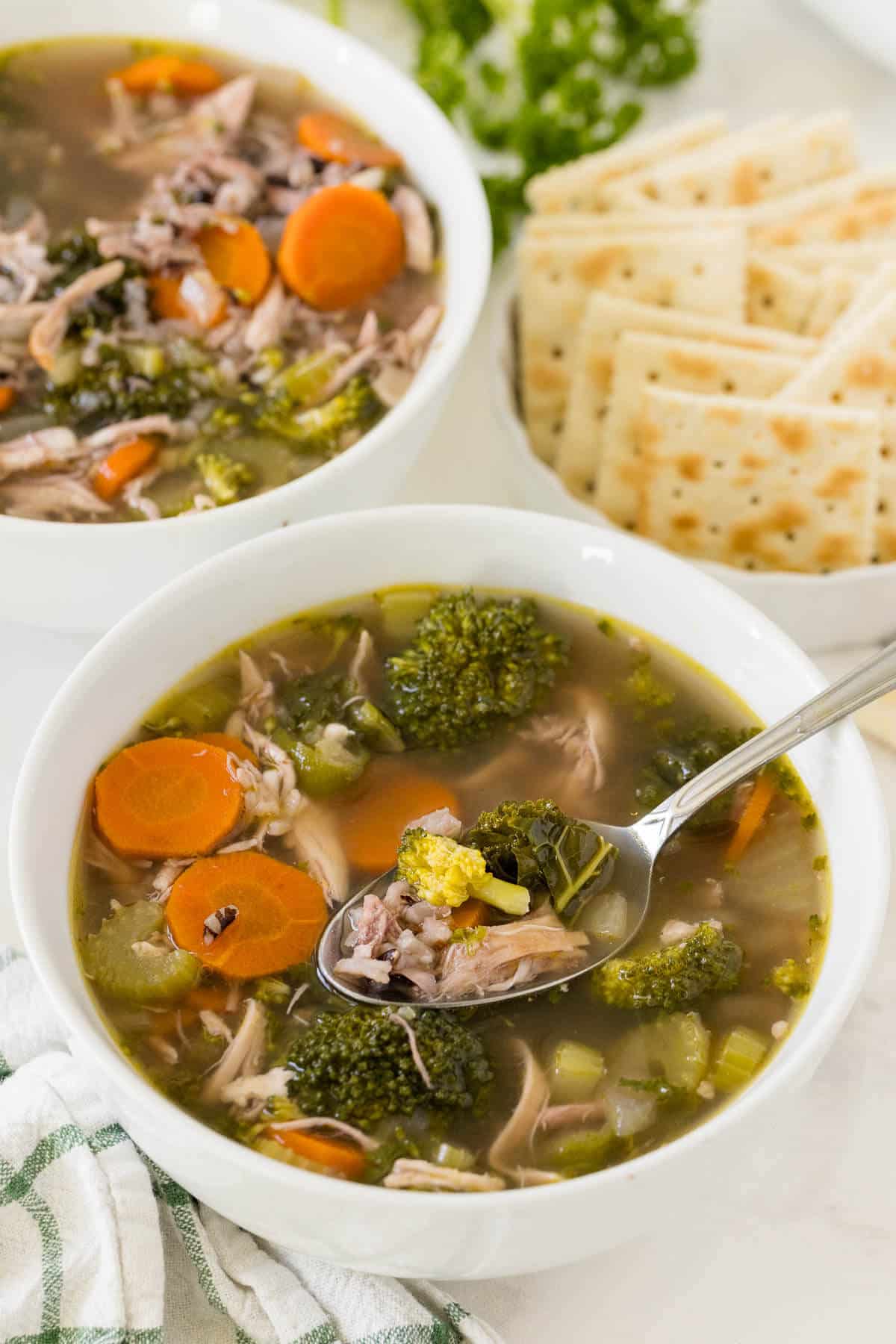 A bowl of very veggie chicken and rice soup with a spoon.