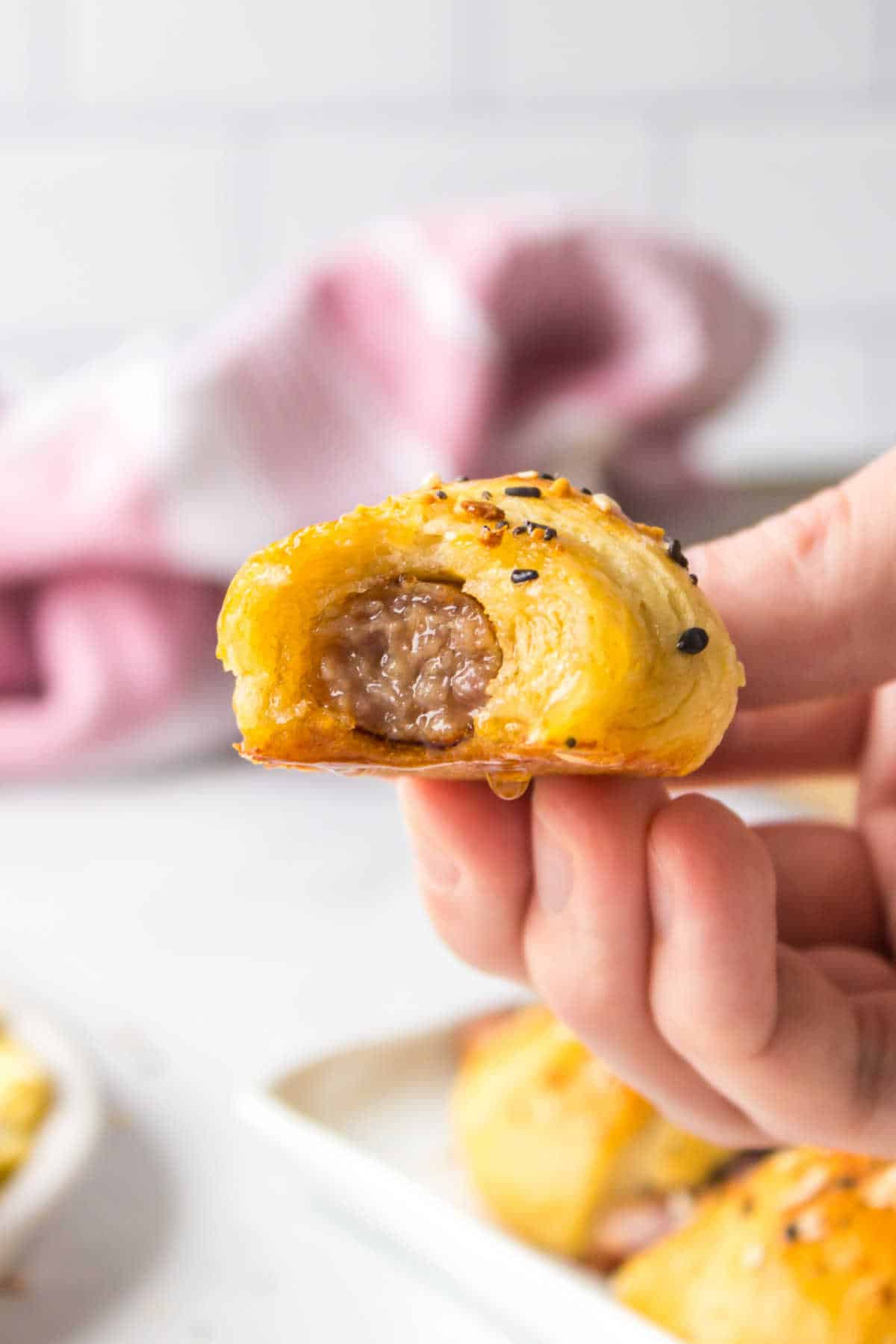 A hand holding a breakfast pig in a blanket.