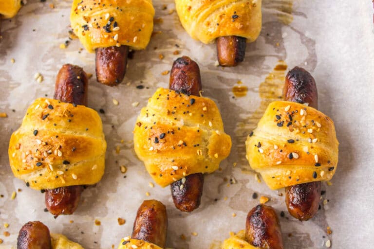 Breakfast pigs in a blanket on a baking sheet.