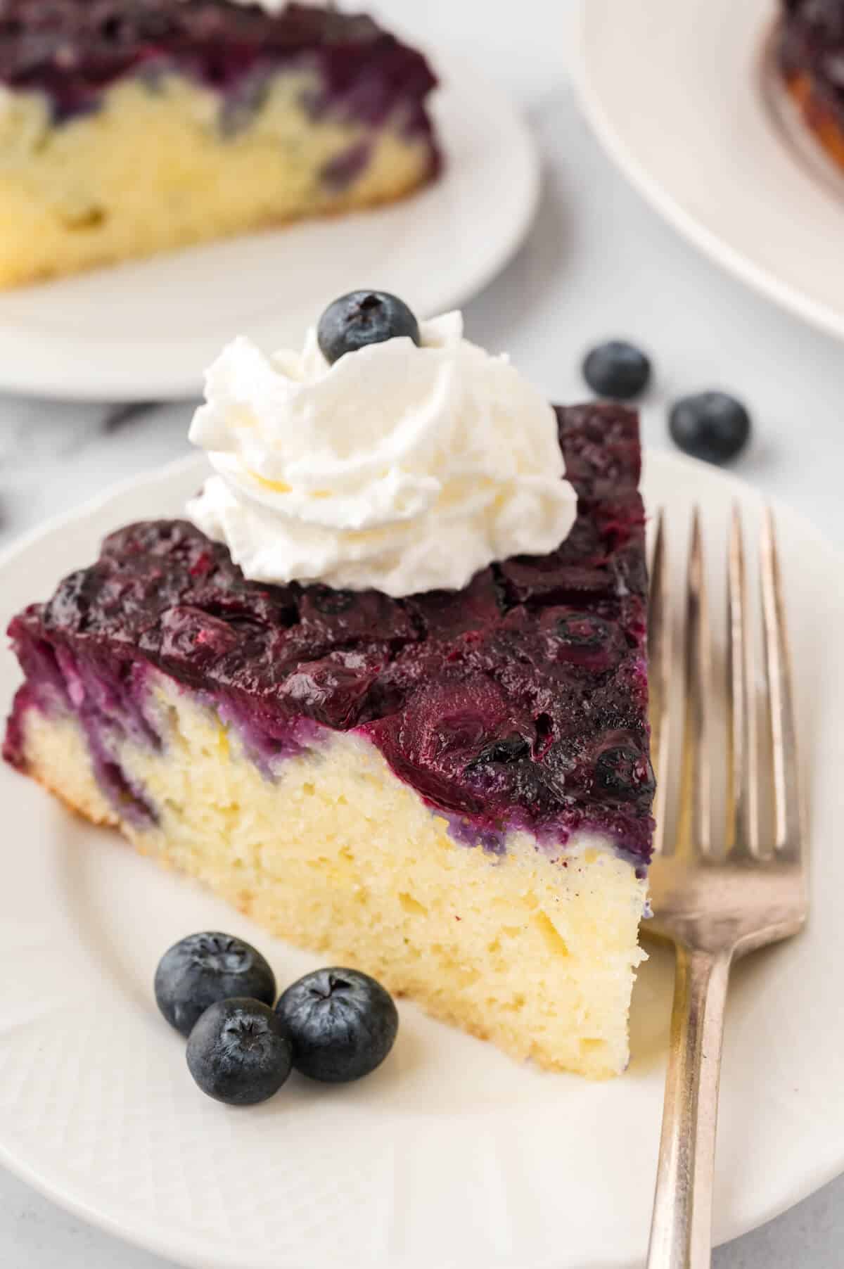 A slice of blueberry upside down cake on a plate with a fork.