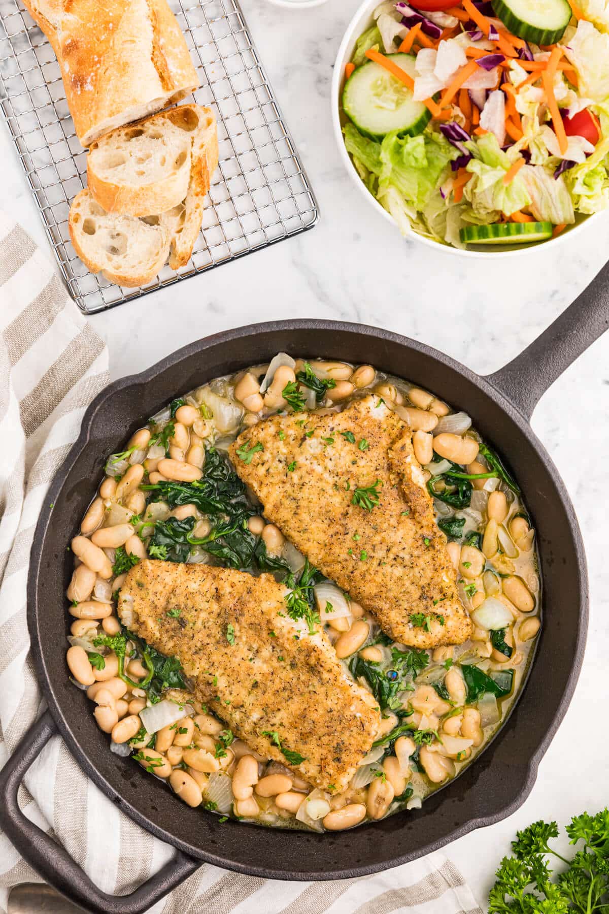 Haddock with spinach and white bean ragout in a cast iron skillet.