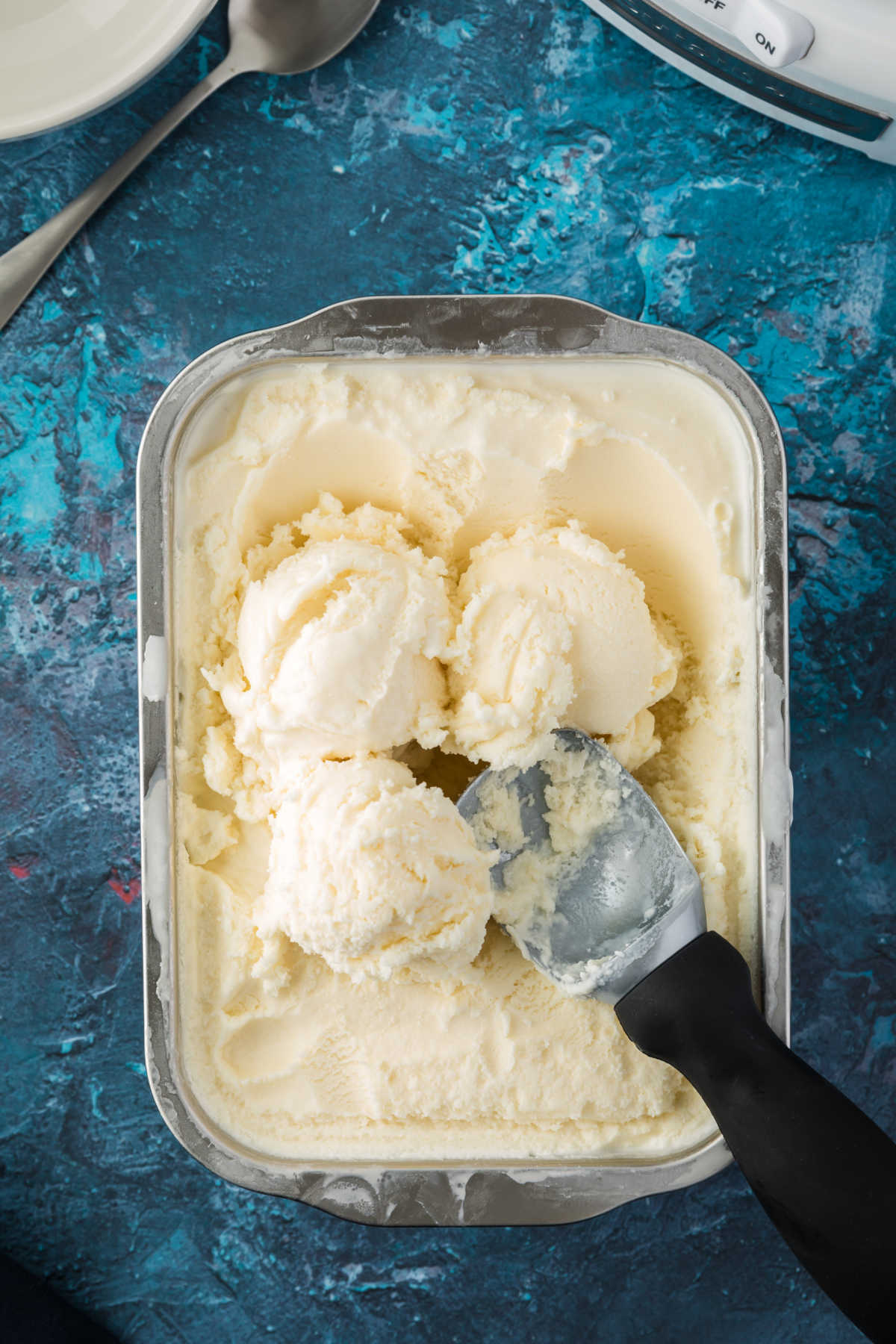 Homemade vanilla ice cream in a tub with an ice cream scoop.