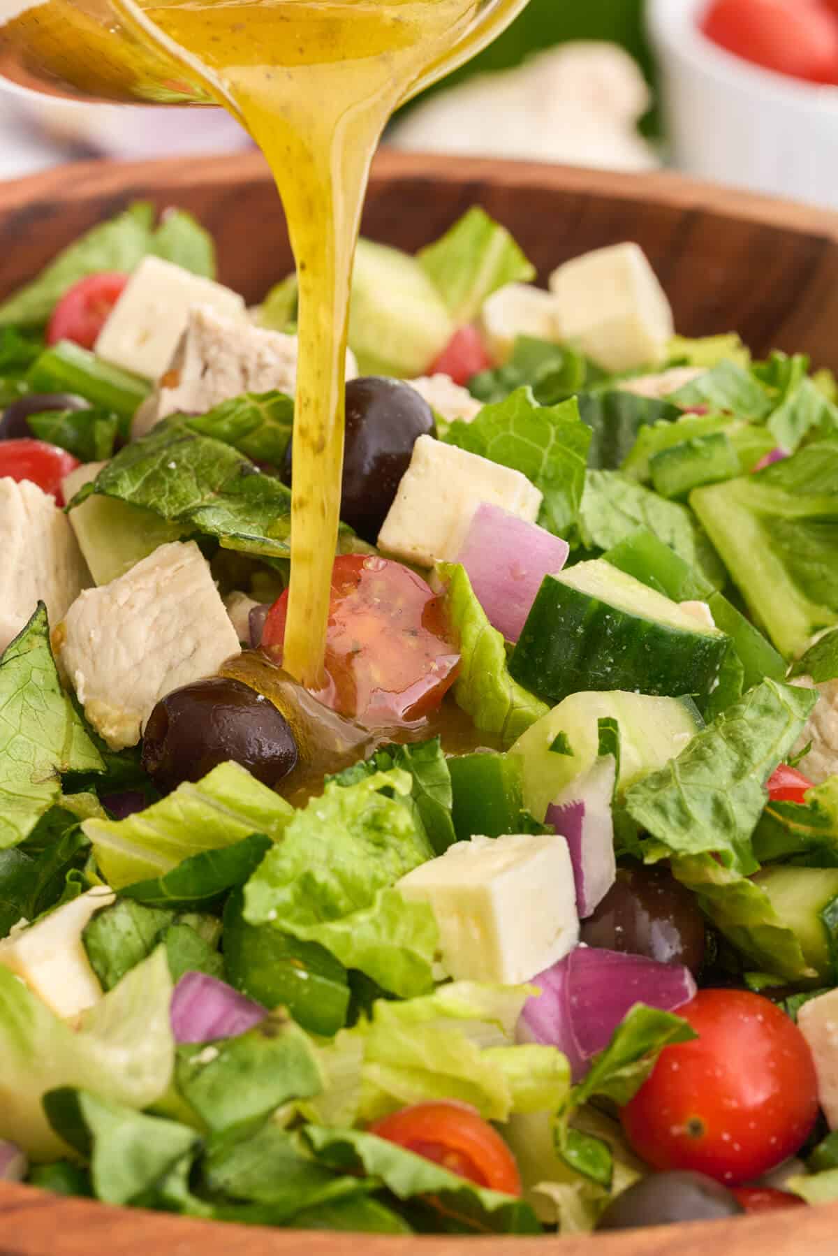 Greek vinaigrette being poured on top of Greek Chicken Salad.