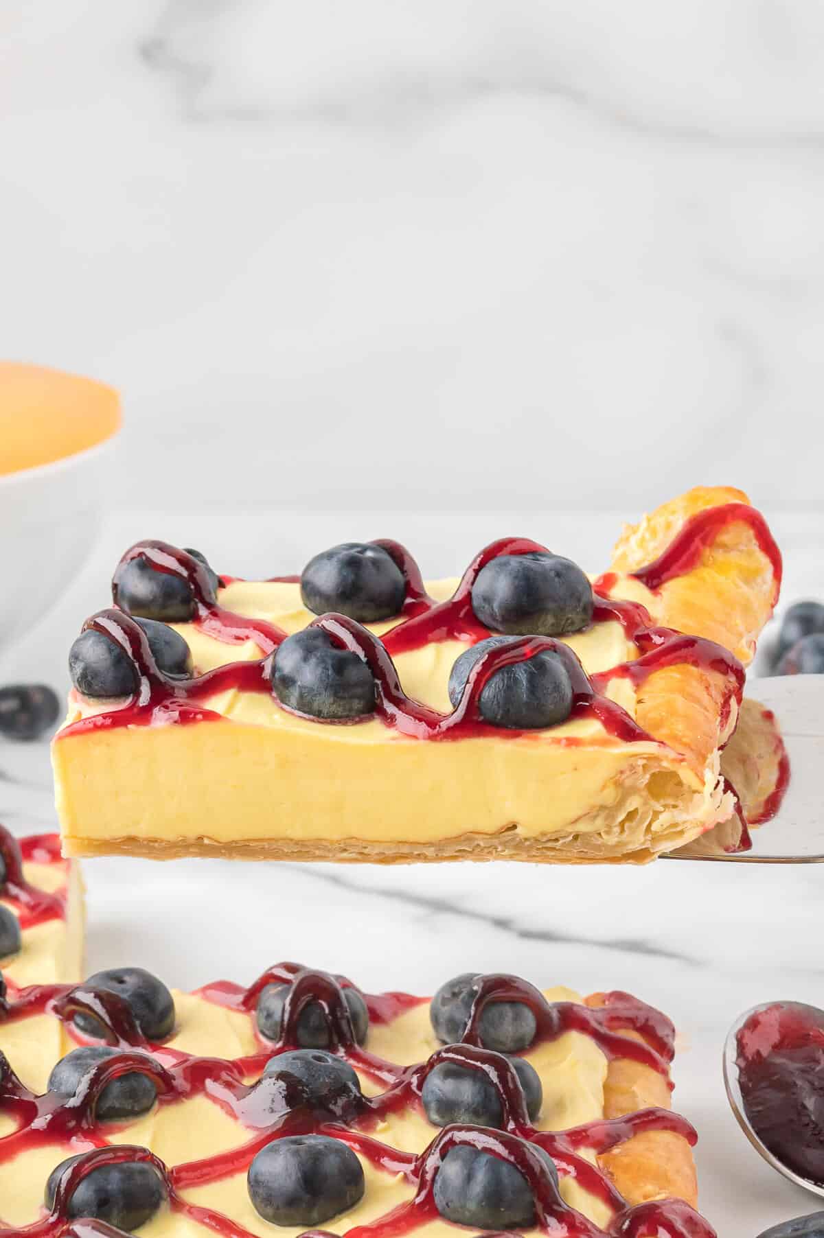 A slice of blueberry lemon tart on a spatula.