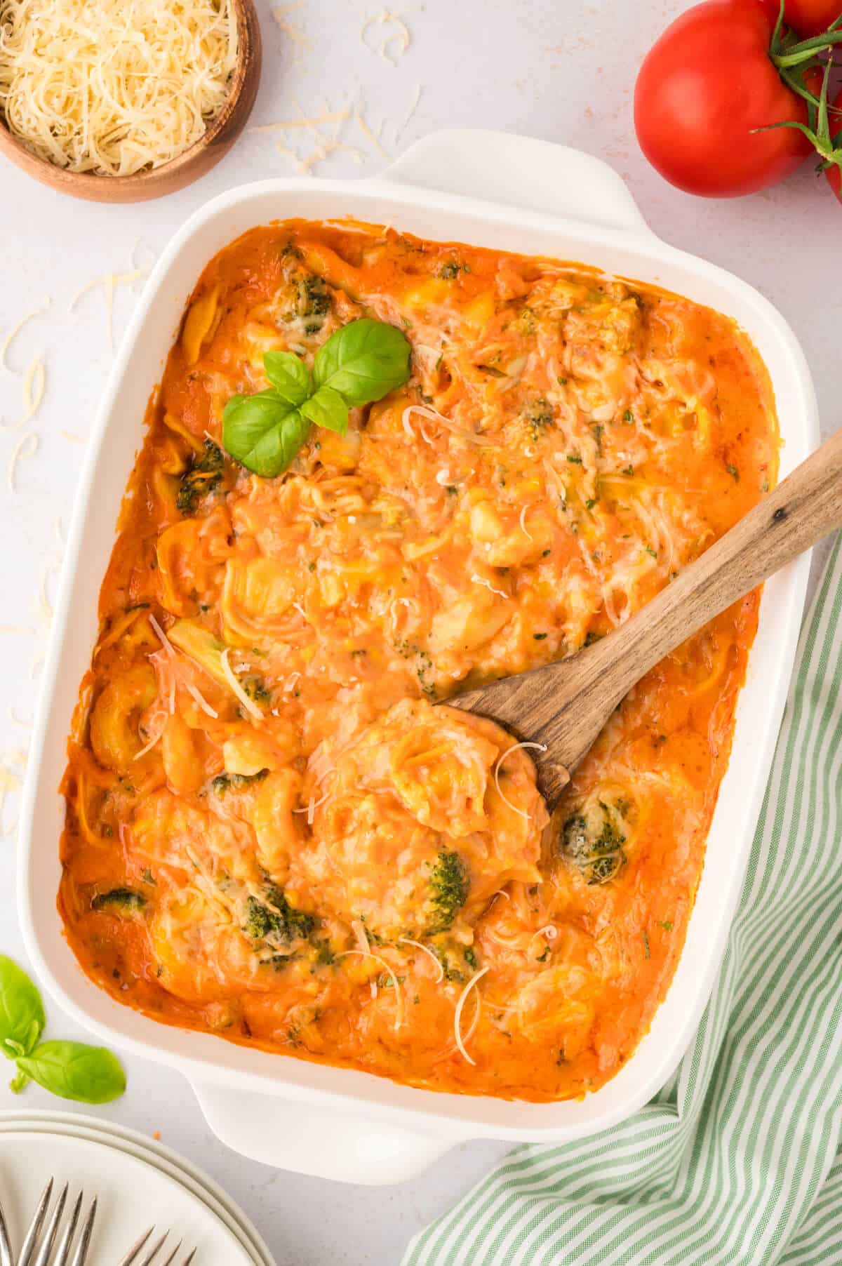 Tortellini casserole in a white casserole dish with a wooden spoon.