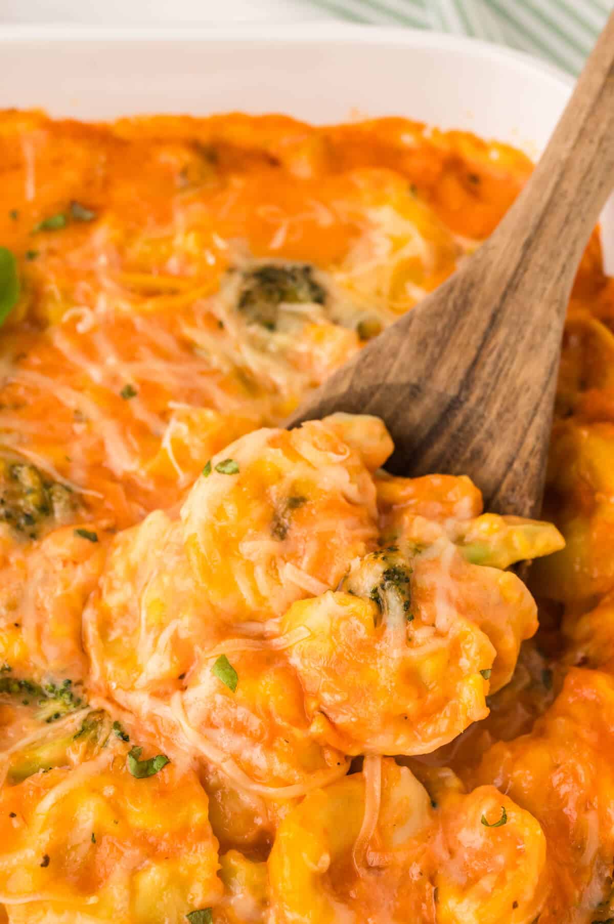 Tortellini casserole in a pan with a wooden spoon.