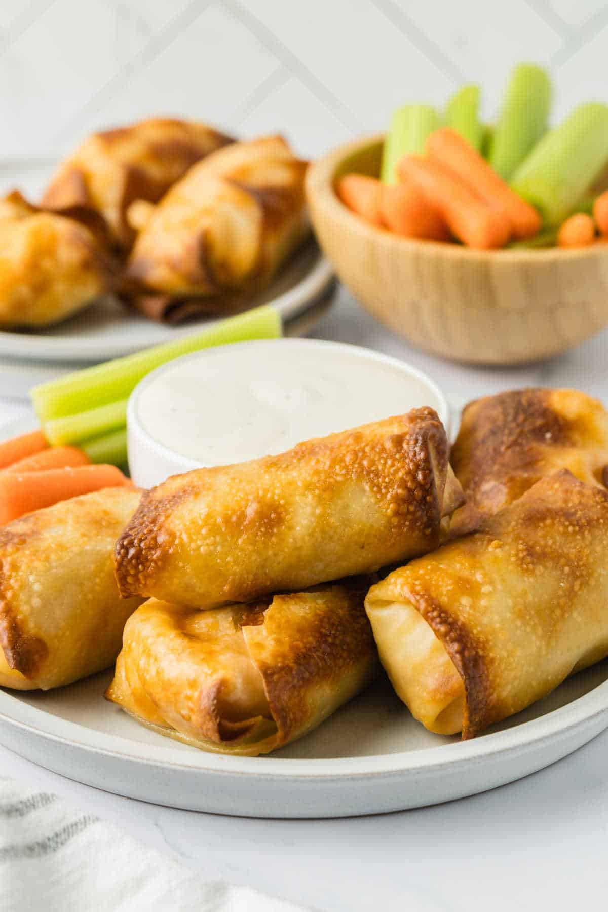 Buffalo chicken egg rolls on a plate with ranch dressing.