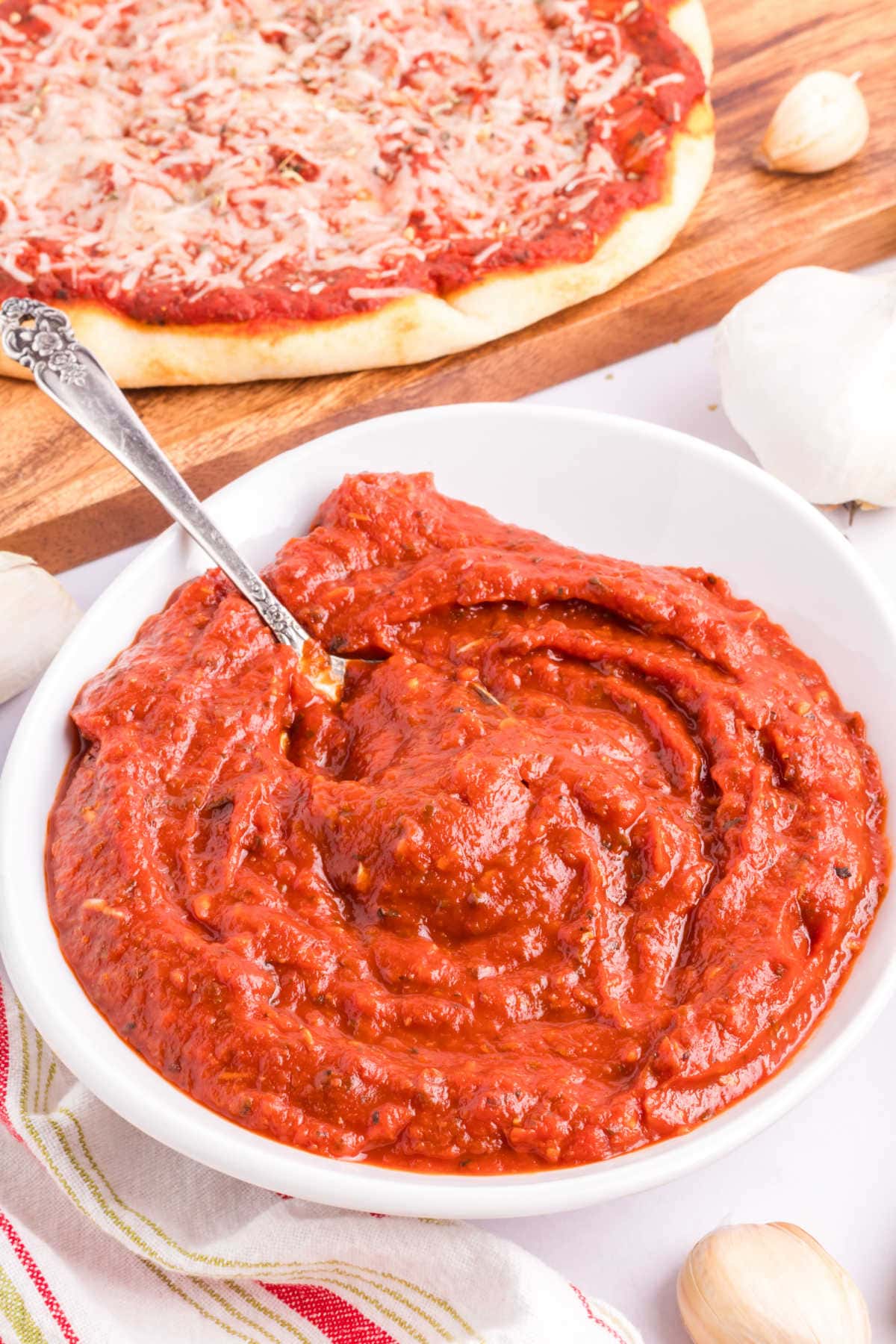 Pizza sauce in a bowl with a spoon.