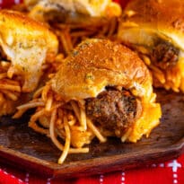 Spaghetti and meatball sliders on a wooden platter.