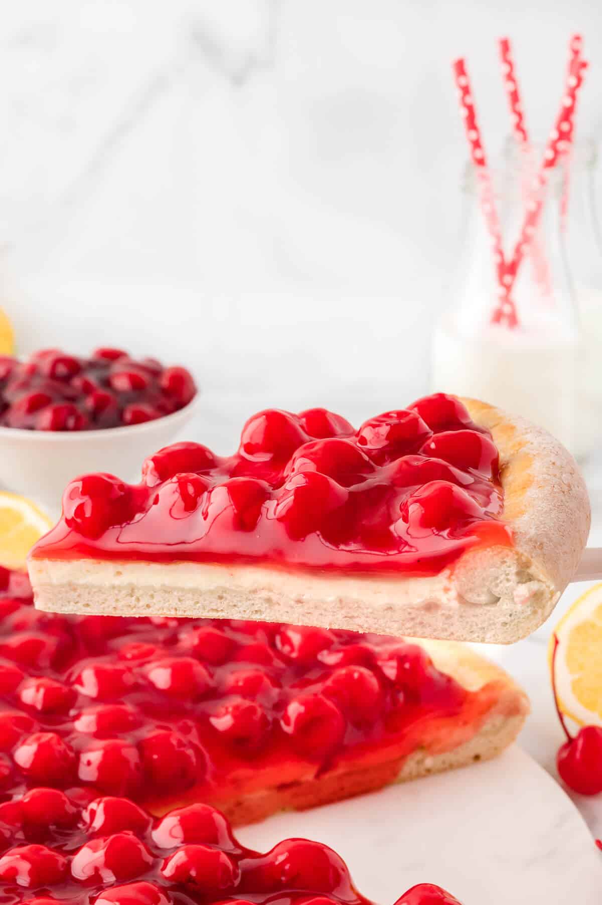 A slice of cherry cheesecake pizza on a spatula.