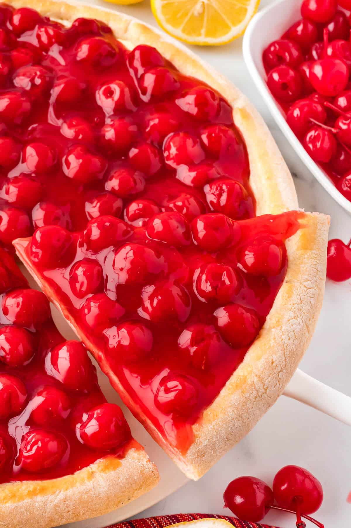 A slice of cherry cheesecake pizza on a spatula.