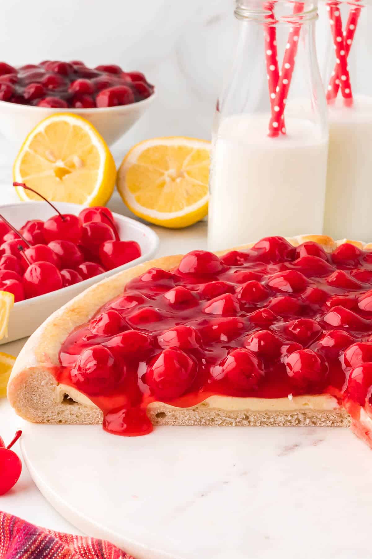 A cherry cheesecake pizza with slices cut out.