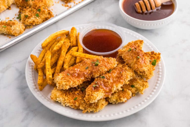 Hot honey chicken tenders on a plate with fries and hot honey sauce.