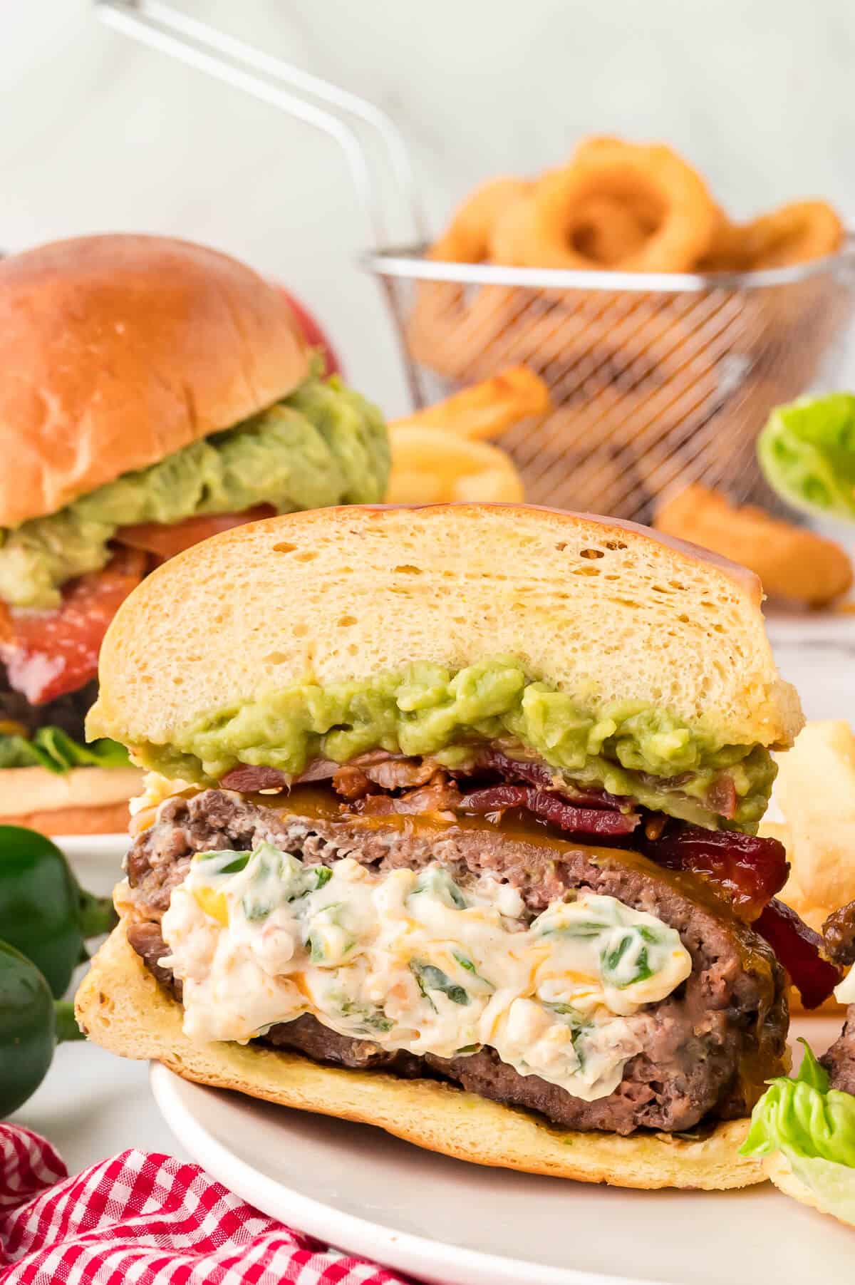 A Cream Cheese Stuffed Jalapeno Burger cut in half on a plate.