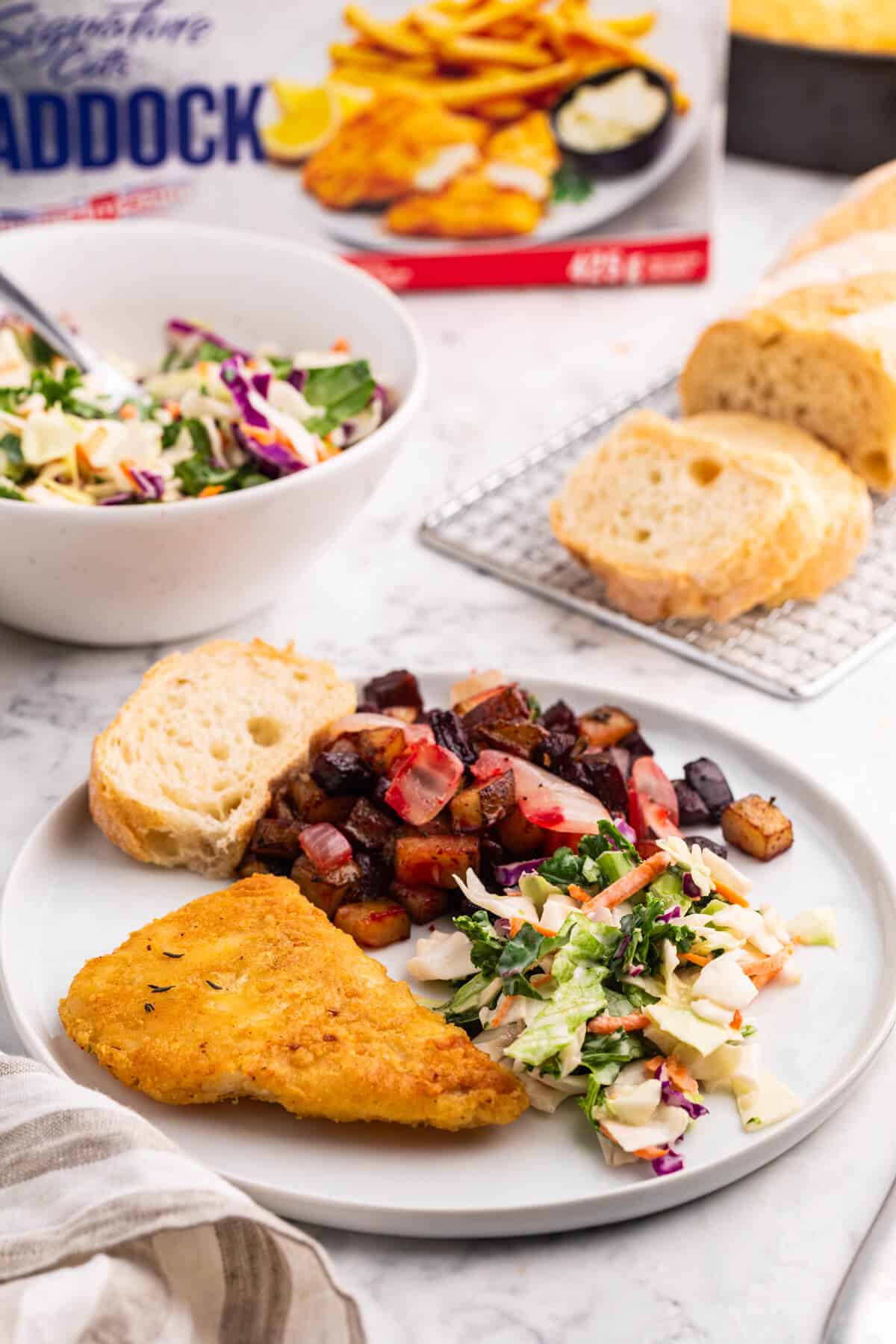 Fish with Beet and Potato Hash on a plate with salad and bread.