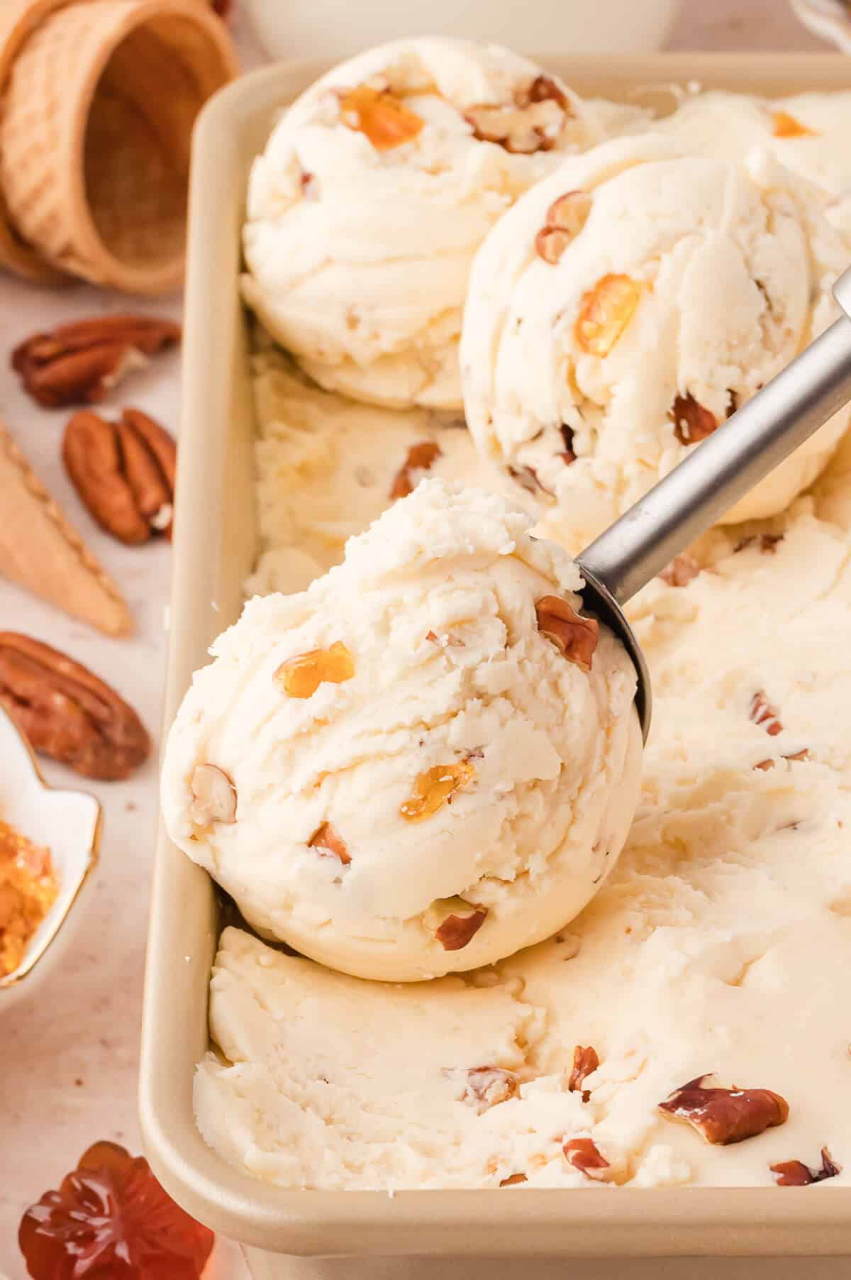 Maple pecan ice cream in a container with an ice cream scoop.