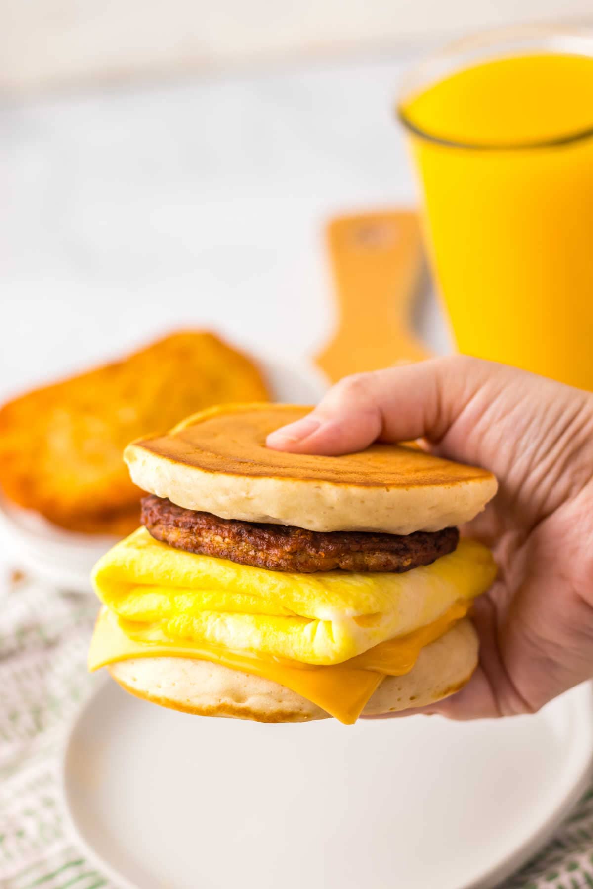 A hand holding a breakfast sandwich.
