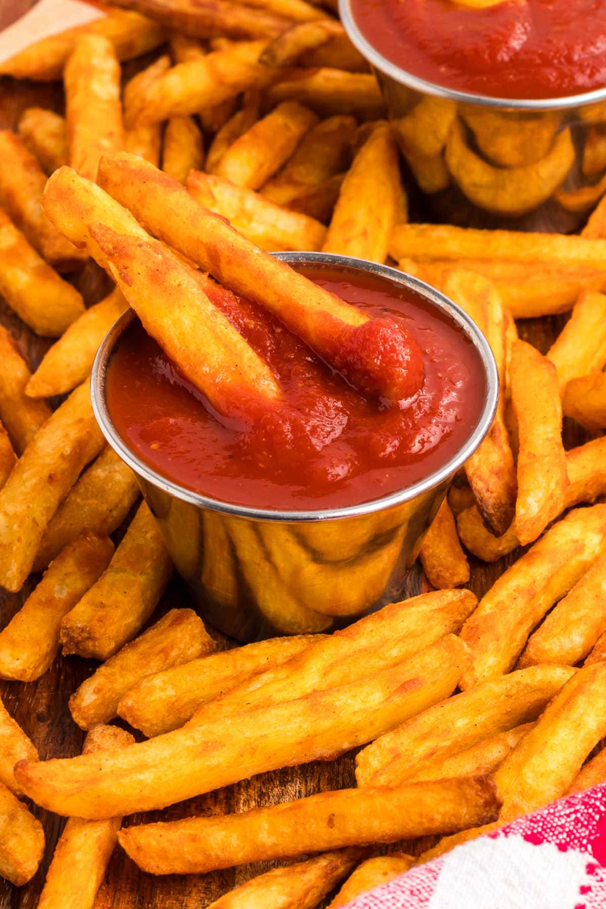 Two fries in a container of homemade ketchup and surrounded by more fries.