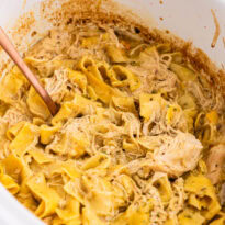 The recipe in a white Crockpot with a serving spoon.