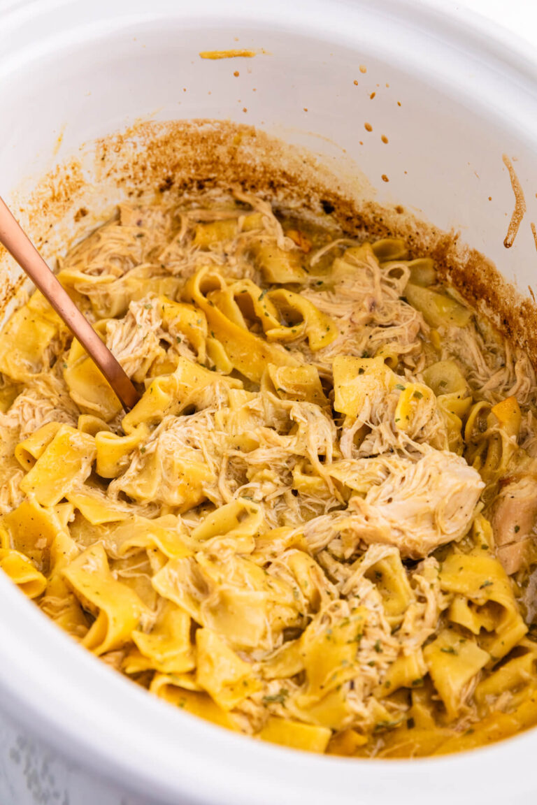 The recipe in a white Crockpot with a serving spoon.