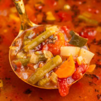 A ladle of soup in a Dutch oven.