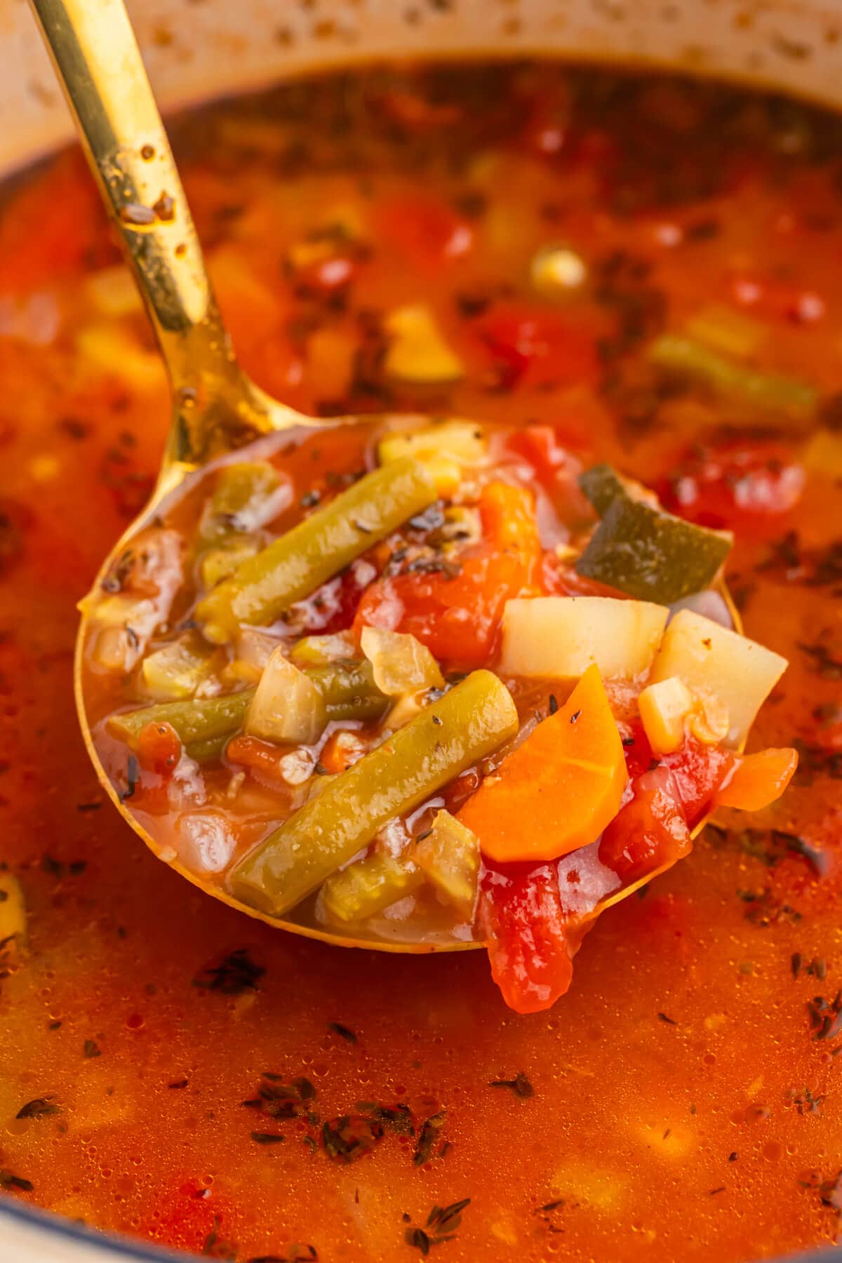 The soup in a ladle over a pot.