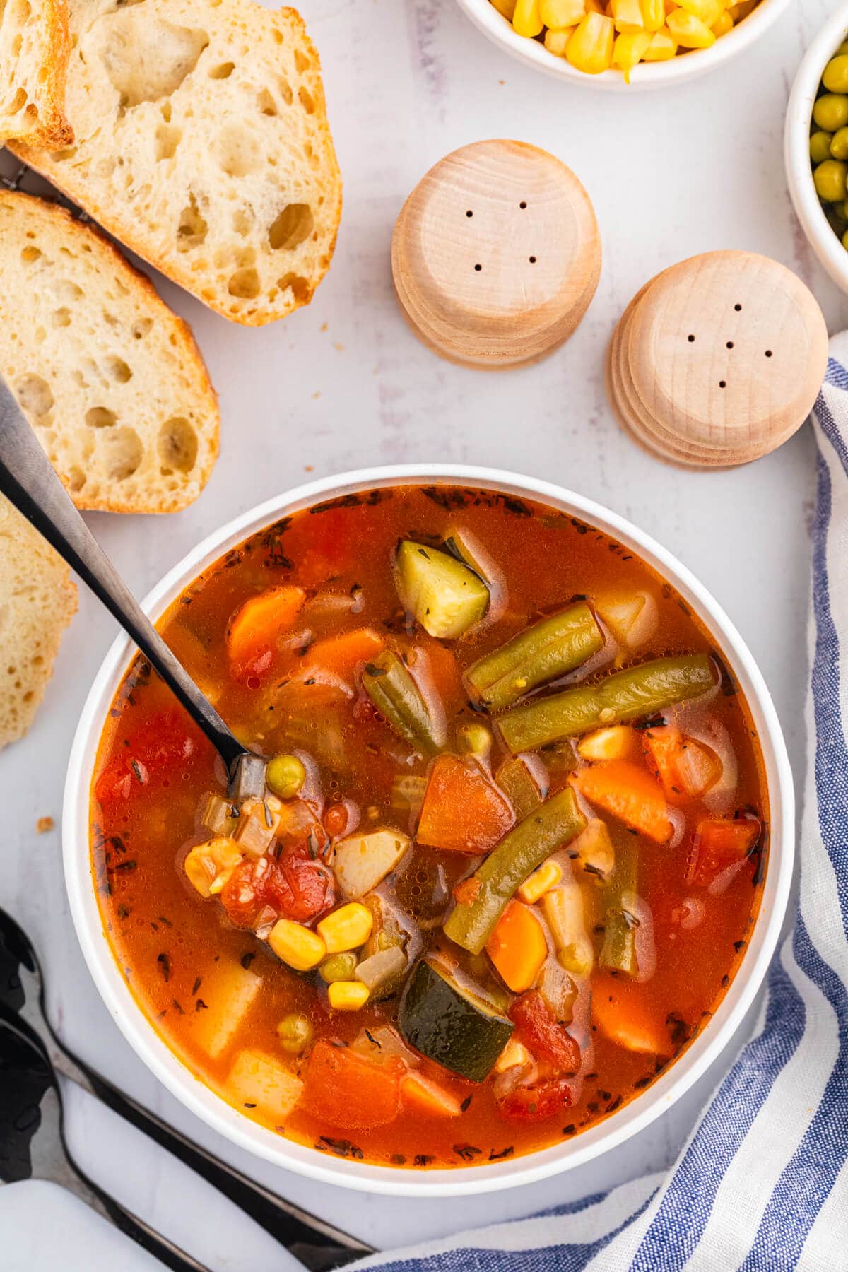 A bowl of vegetable soup with a spoon.