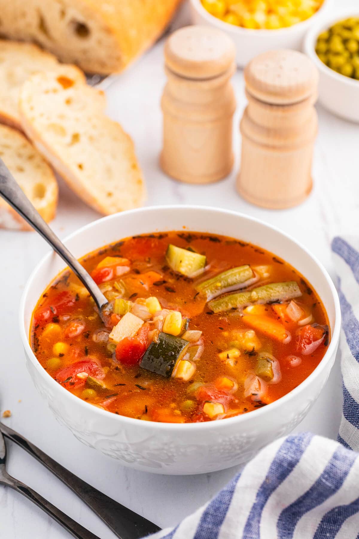 A bowl of vegetable soup with a spoon.