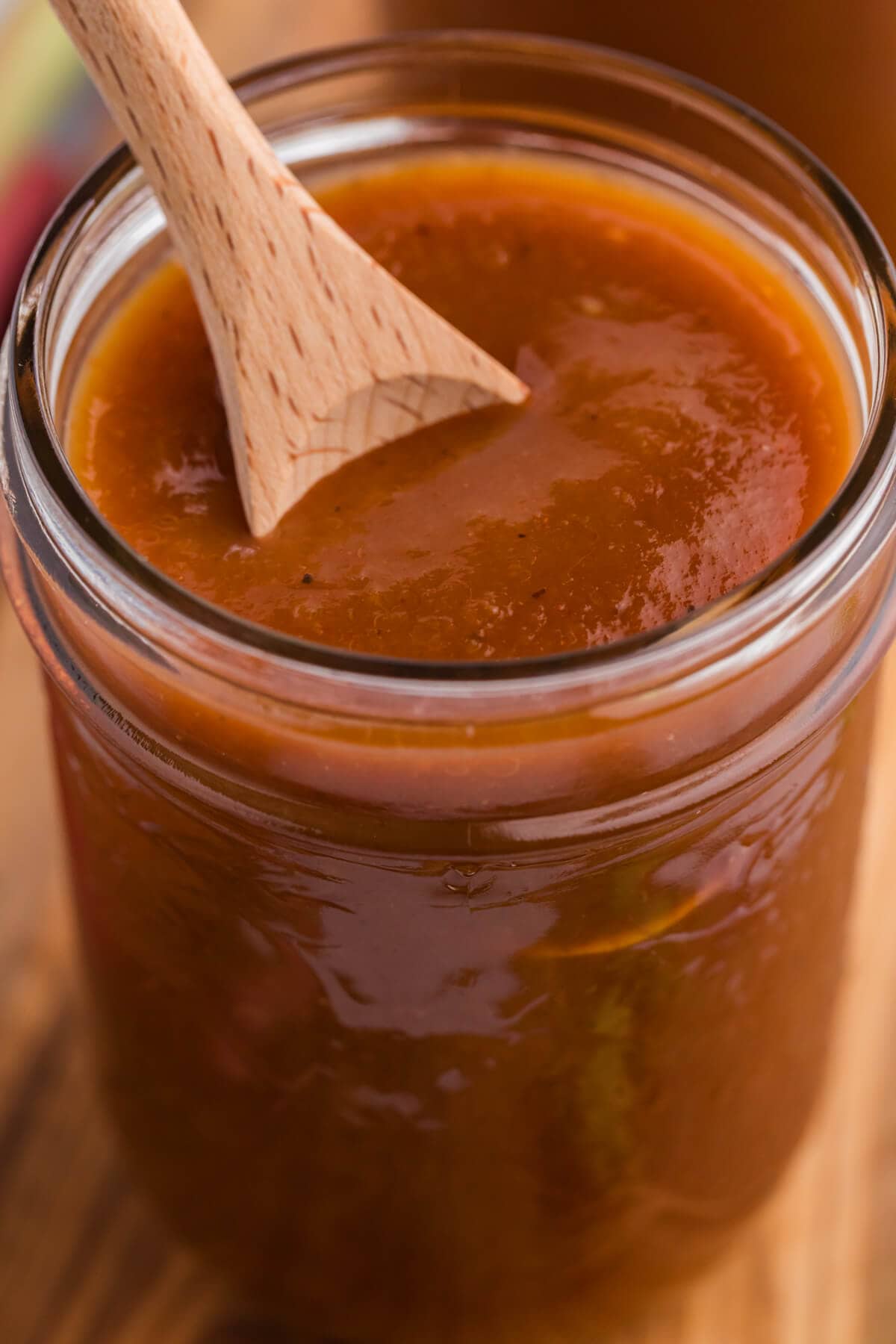 Rhubarb BBQ Sauce in a jar with a wooden spoon.