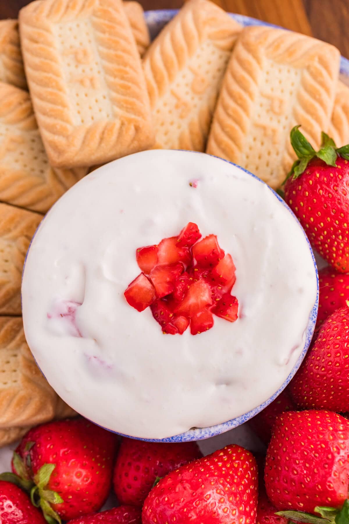 The dip surrounded by cookies and strawberries.
