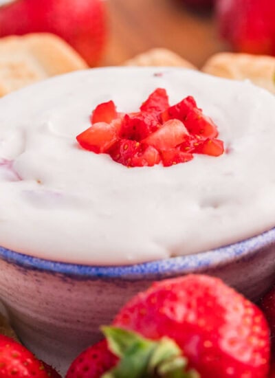 The dip on a platter with cookies and strawberries.
