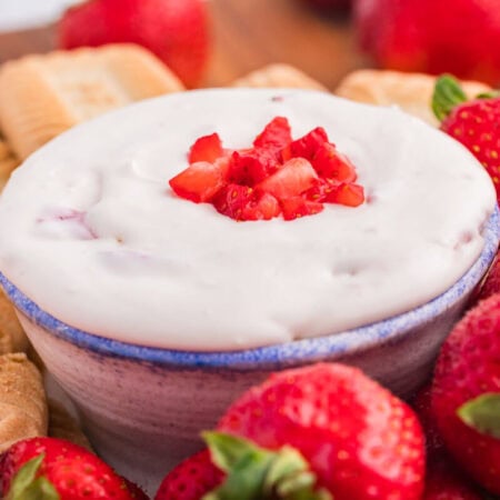 The dip on a platter with cookies and strawberries.