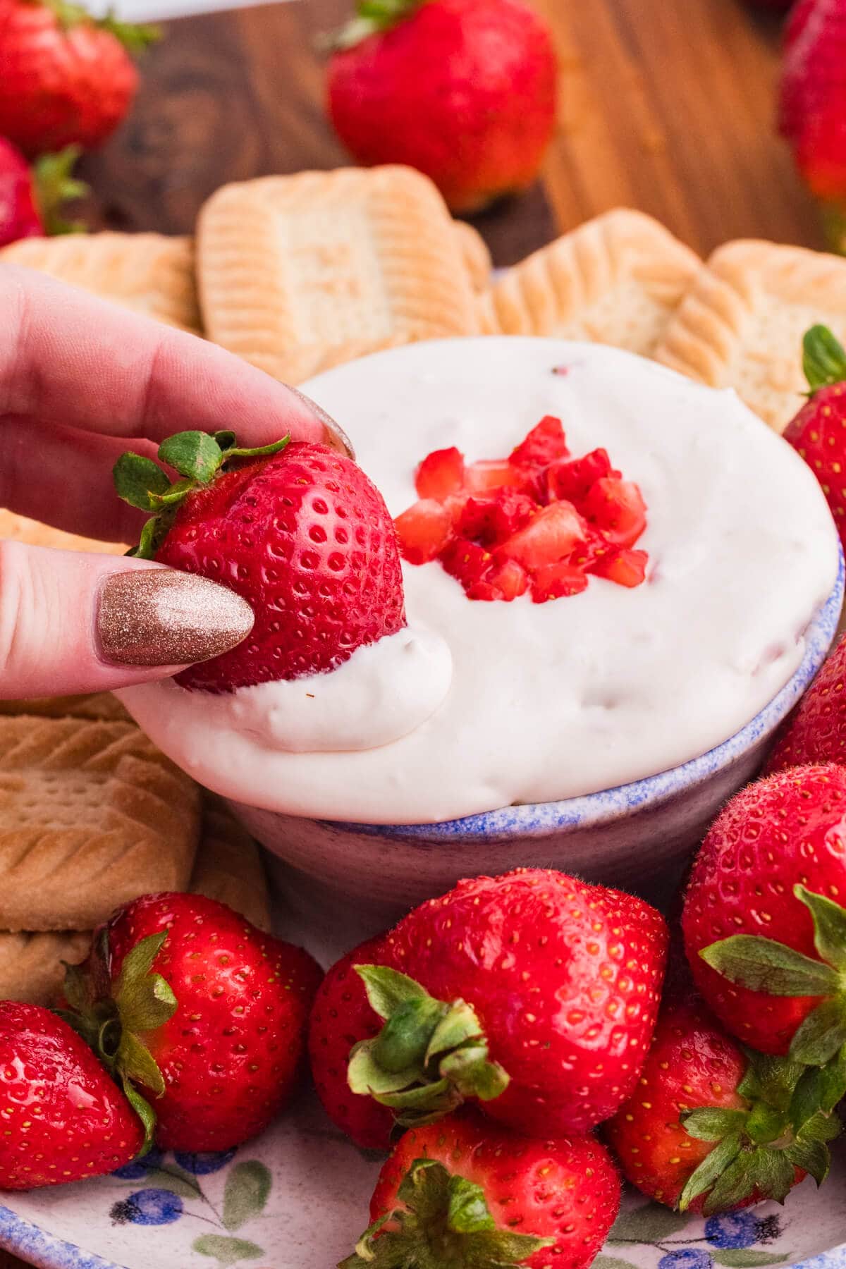 A hand dipping a strawberry in the dip.