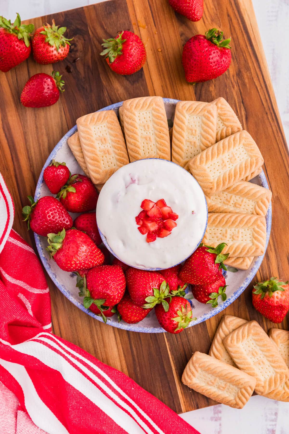 The dip on a platter with cookies and strawberries.