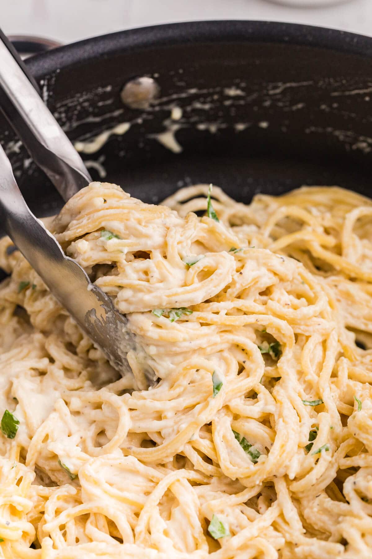 Tongs in a skillet of the recipe.