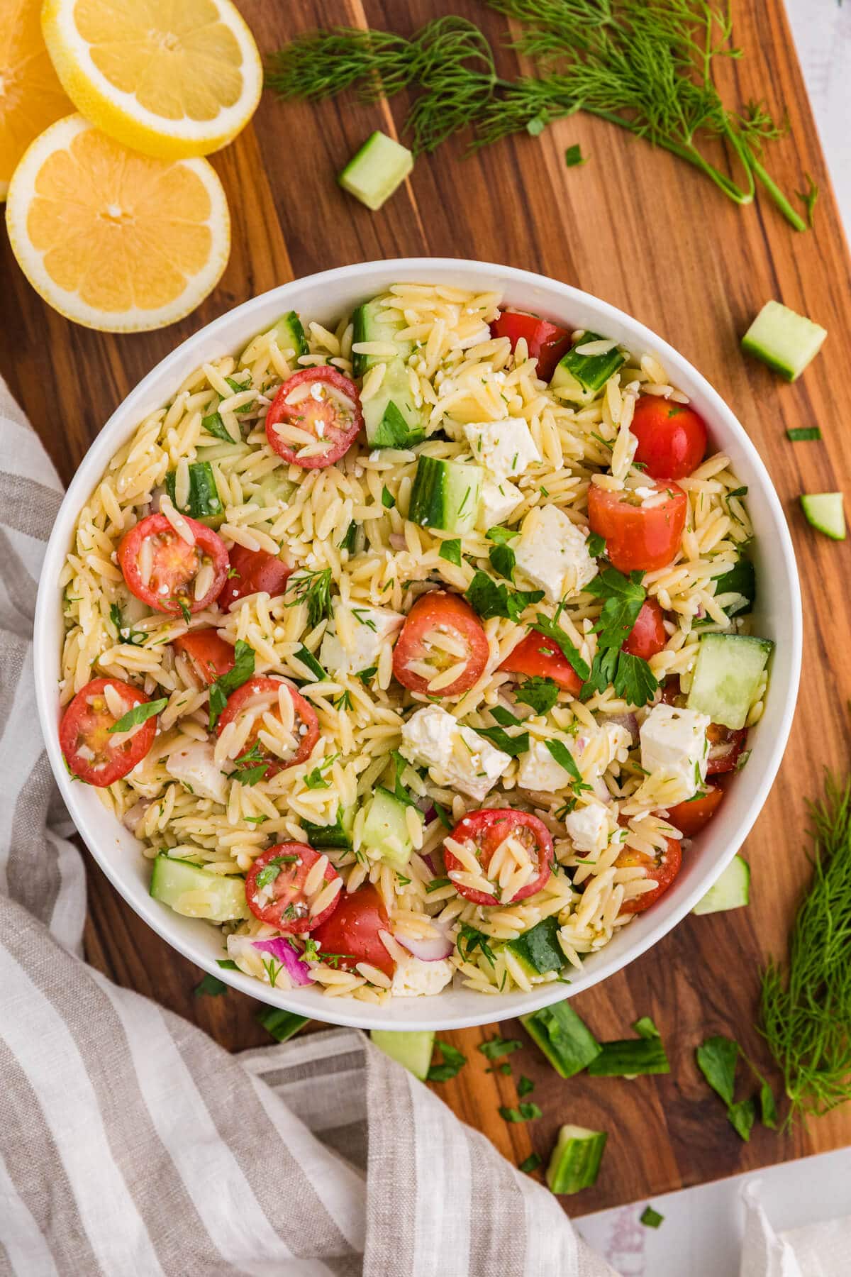 Lemon herb orzo salad on a wooden cutting board.