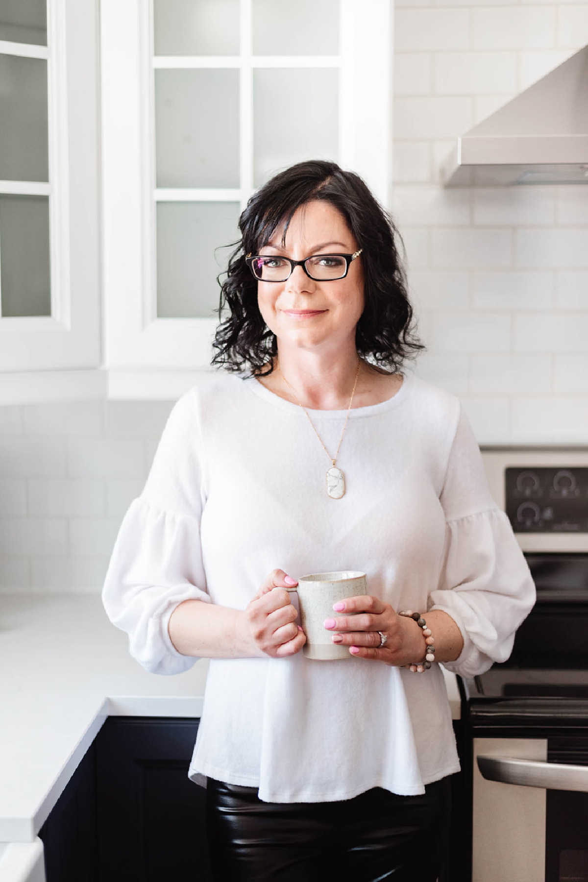 Stacie Vaughan in a white kitchen holding a coffee mug.