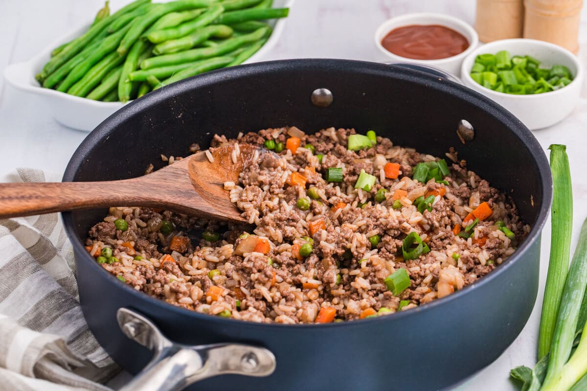 BBQ Beef and Rice in a skillet with a wooden serving spoon.