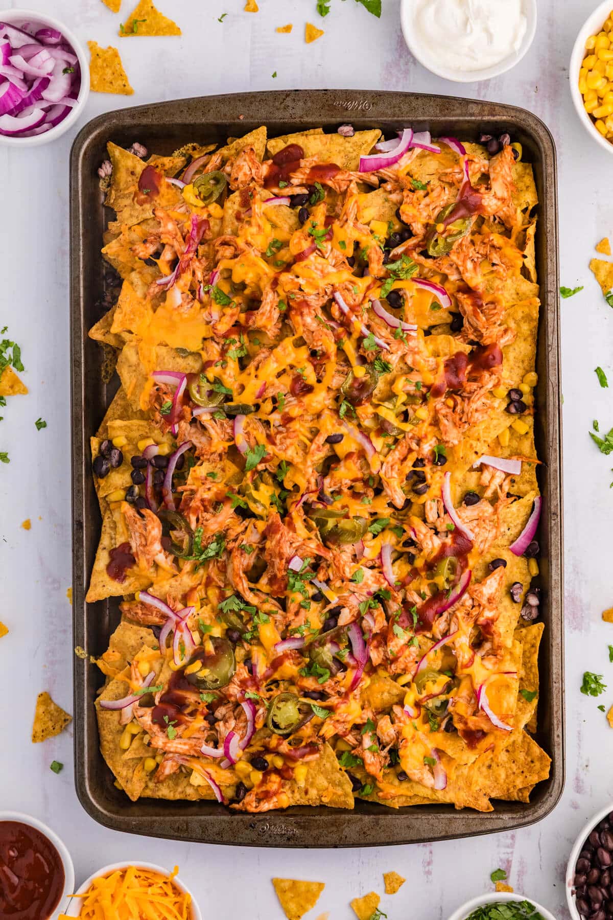 BBQ Chicken Nachos on a sheet pan on a white surface.