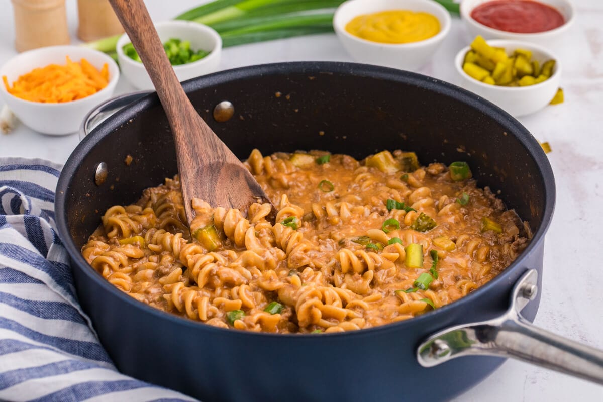 Cheeseburger Pasta Skillet in a dark pan with a wooden spoon.