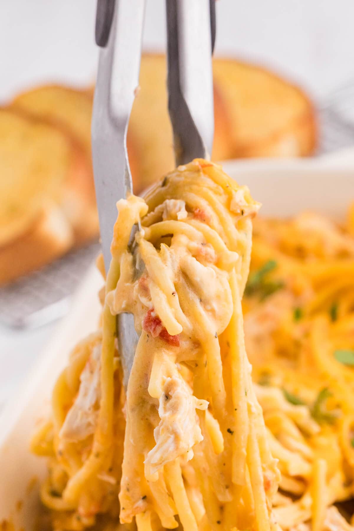 The recipe being lifted out of a skillet with tongs.