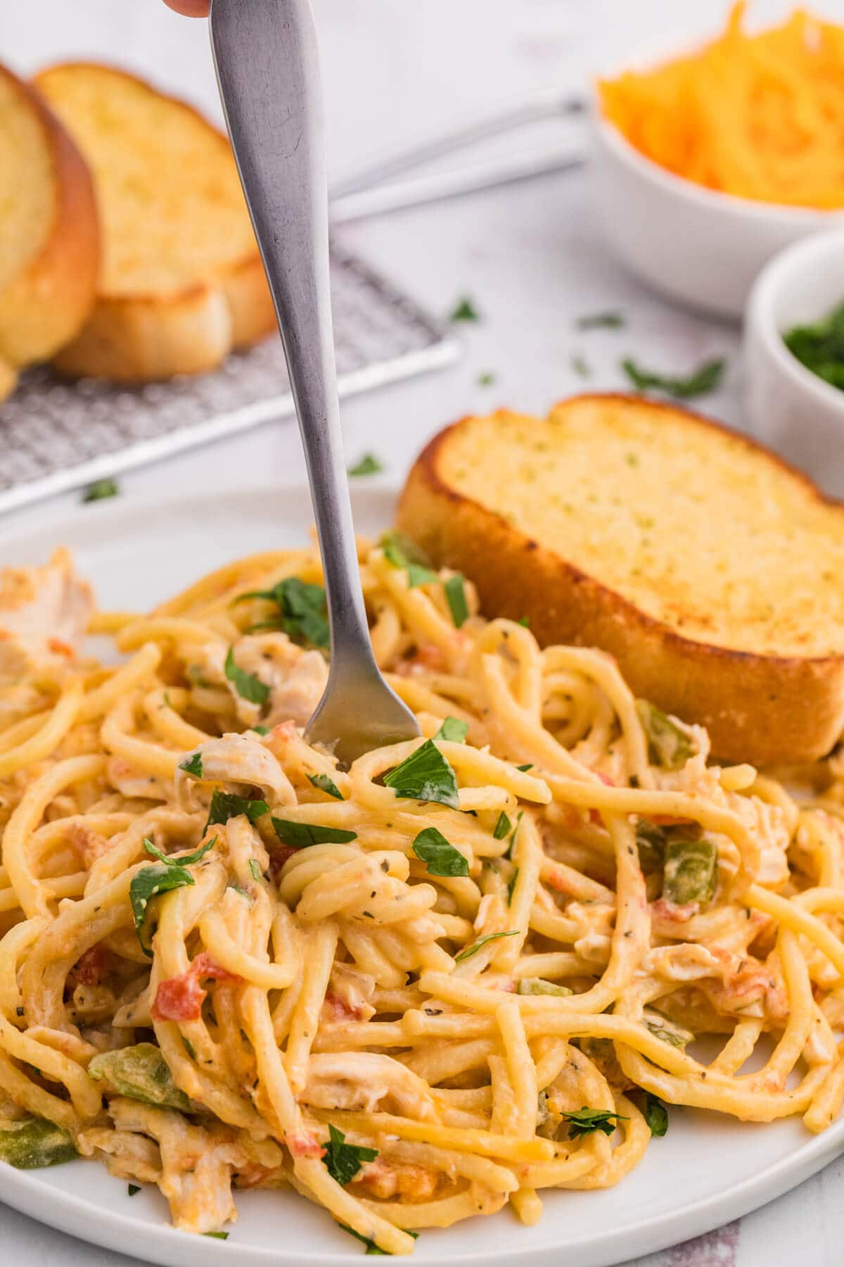 The recipe on a plate with a fork, and a slice of garlic bread.