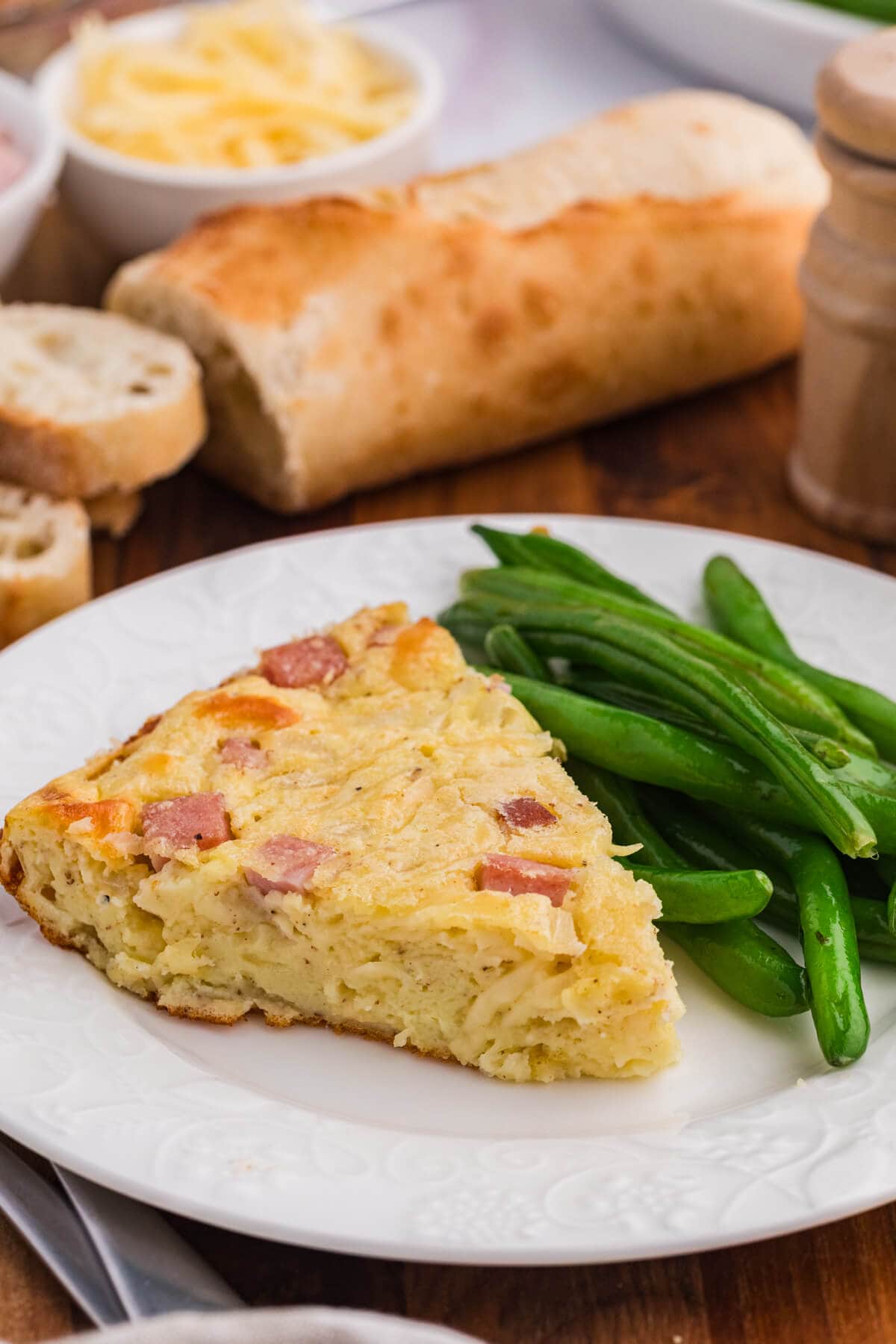 A slice of the recipe on a plate with green beans.