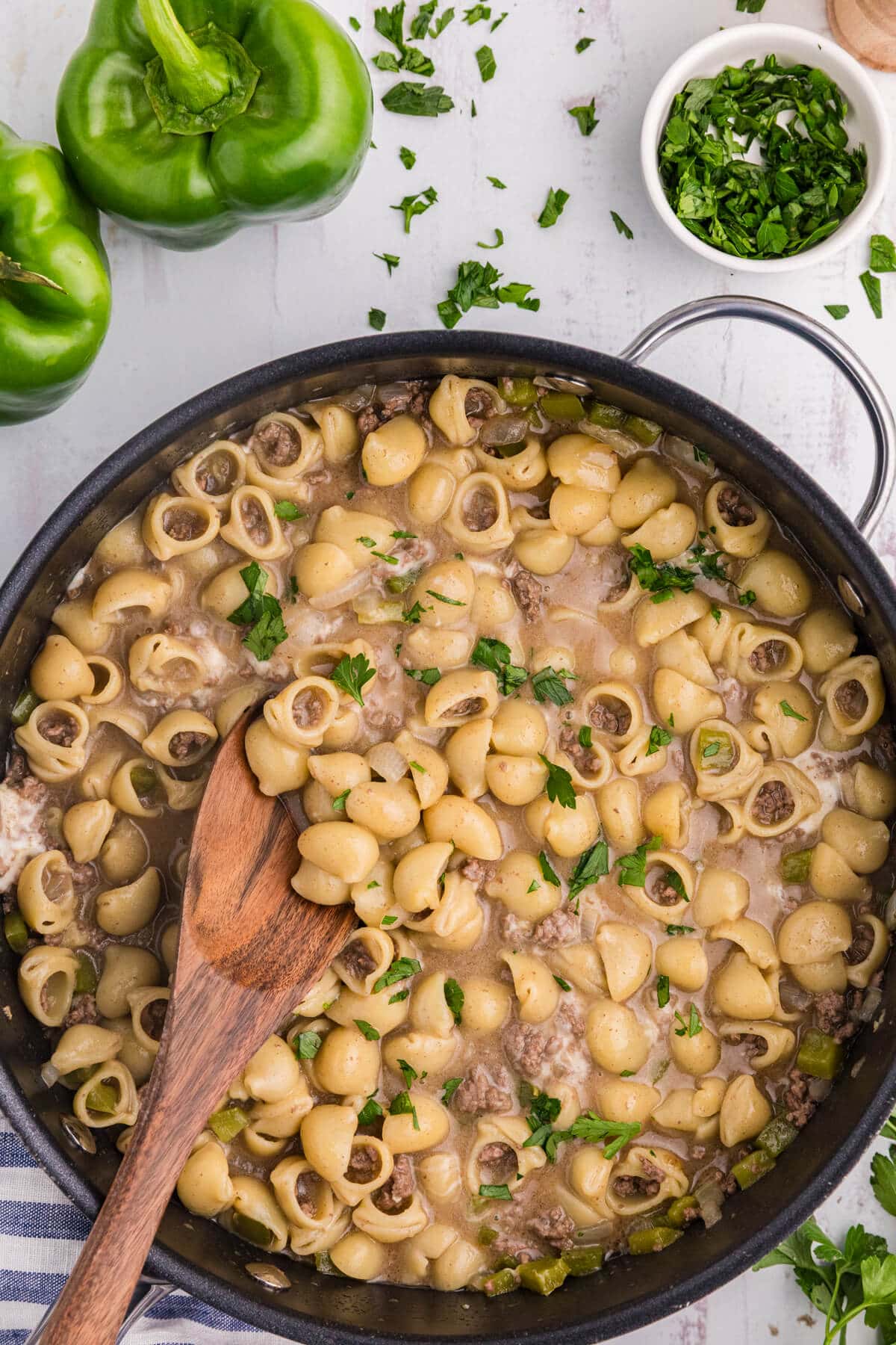 Philly Cheesesteak Pasta in a skillet with a wooden spoon.