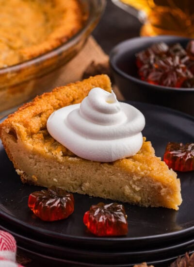 A slice of pie on a plate topped with whipped cream.