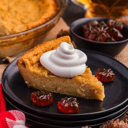 A slice of pie on a plate topped with whipped cream.