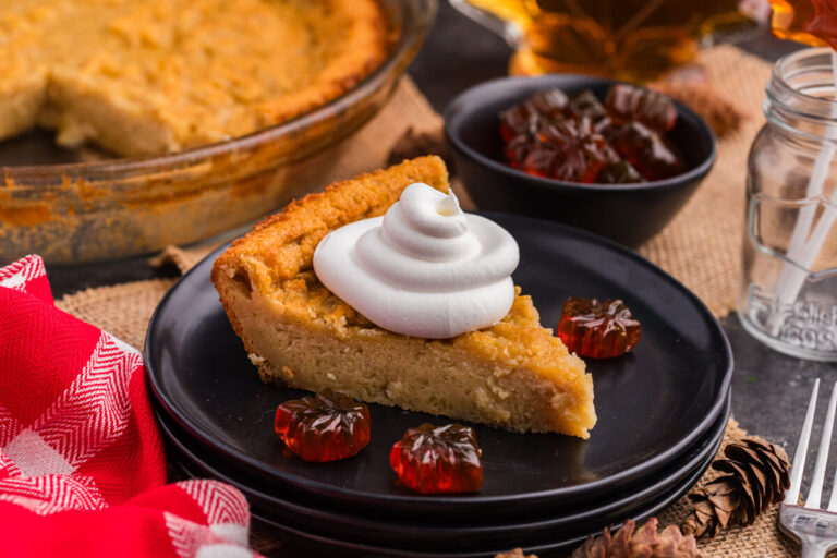 A slice of pie on a plate topped with whipped cream.