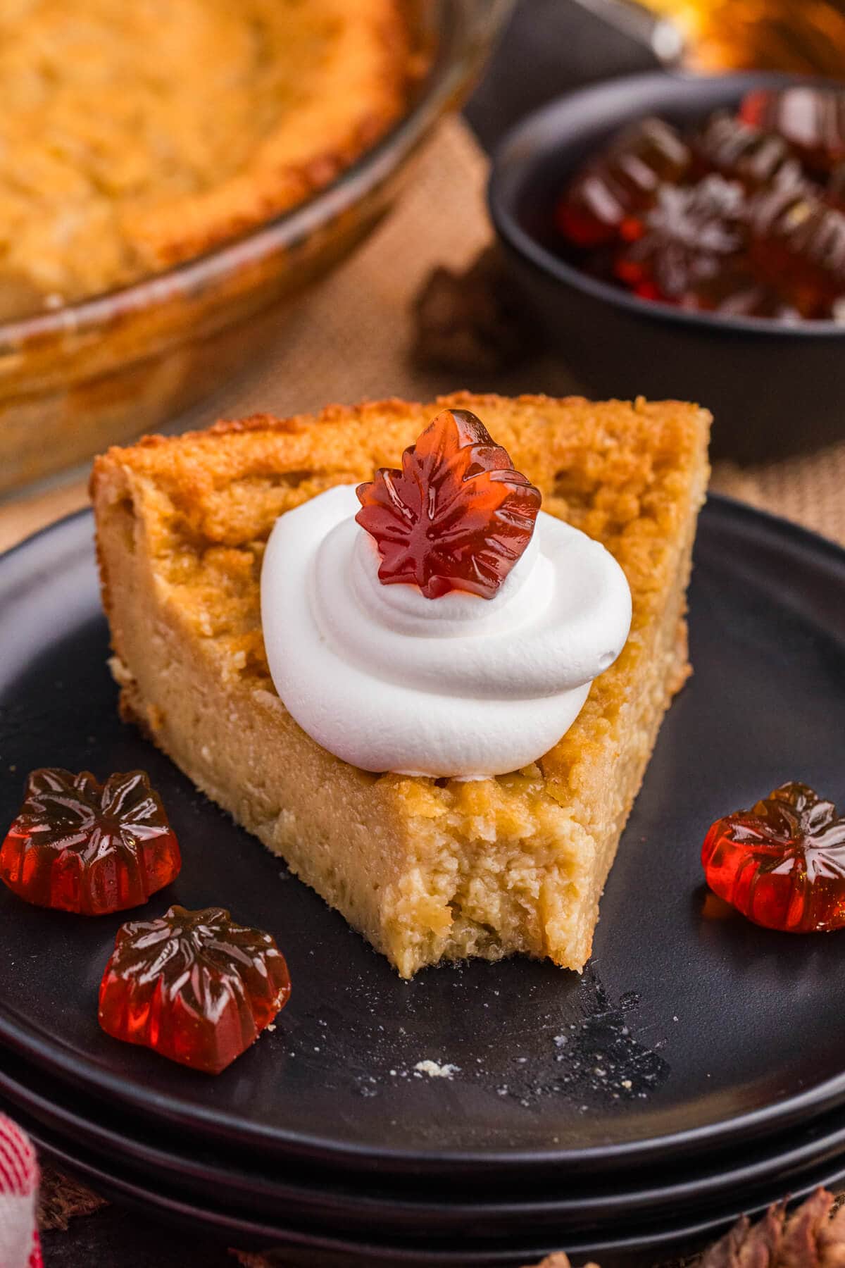 A slice of pie topped with whipped cream and maple candies.