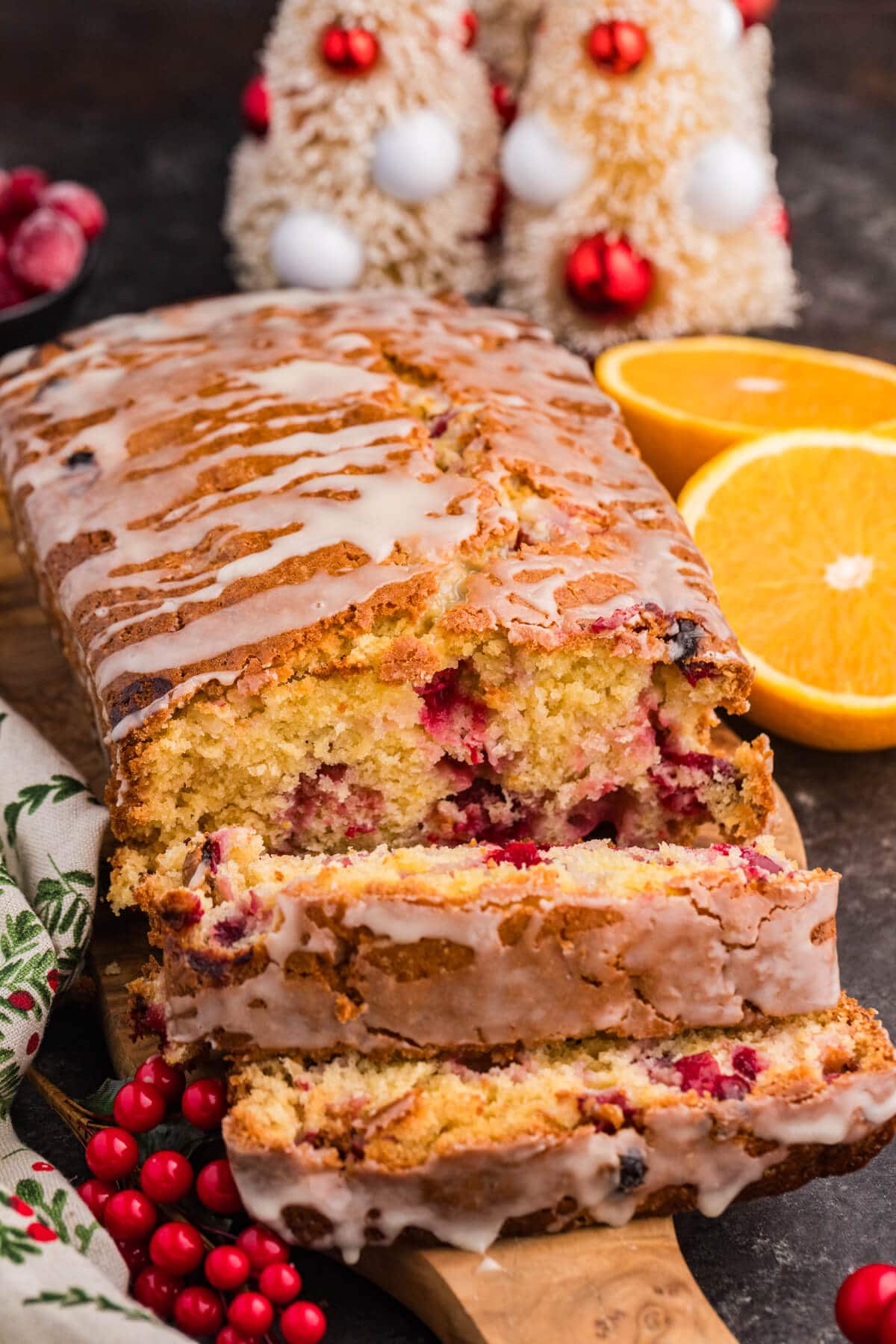 A loaf of cranberry orange bread, featuring a slice cut out to display the colorful cranberries and orange pieces inside.