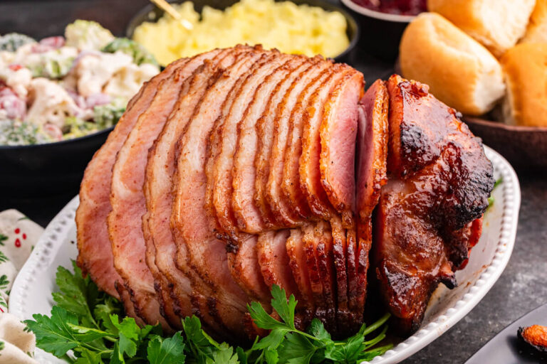 Juicy brown sugar ham, spiral-sliced and glazed to perfection, served on a white platter with fresh parsley garnish.
